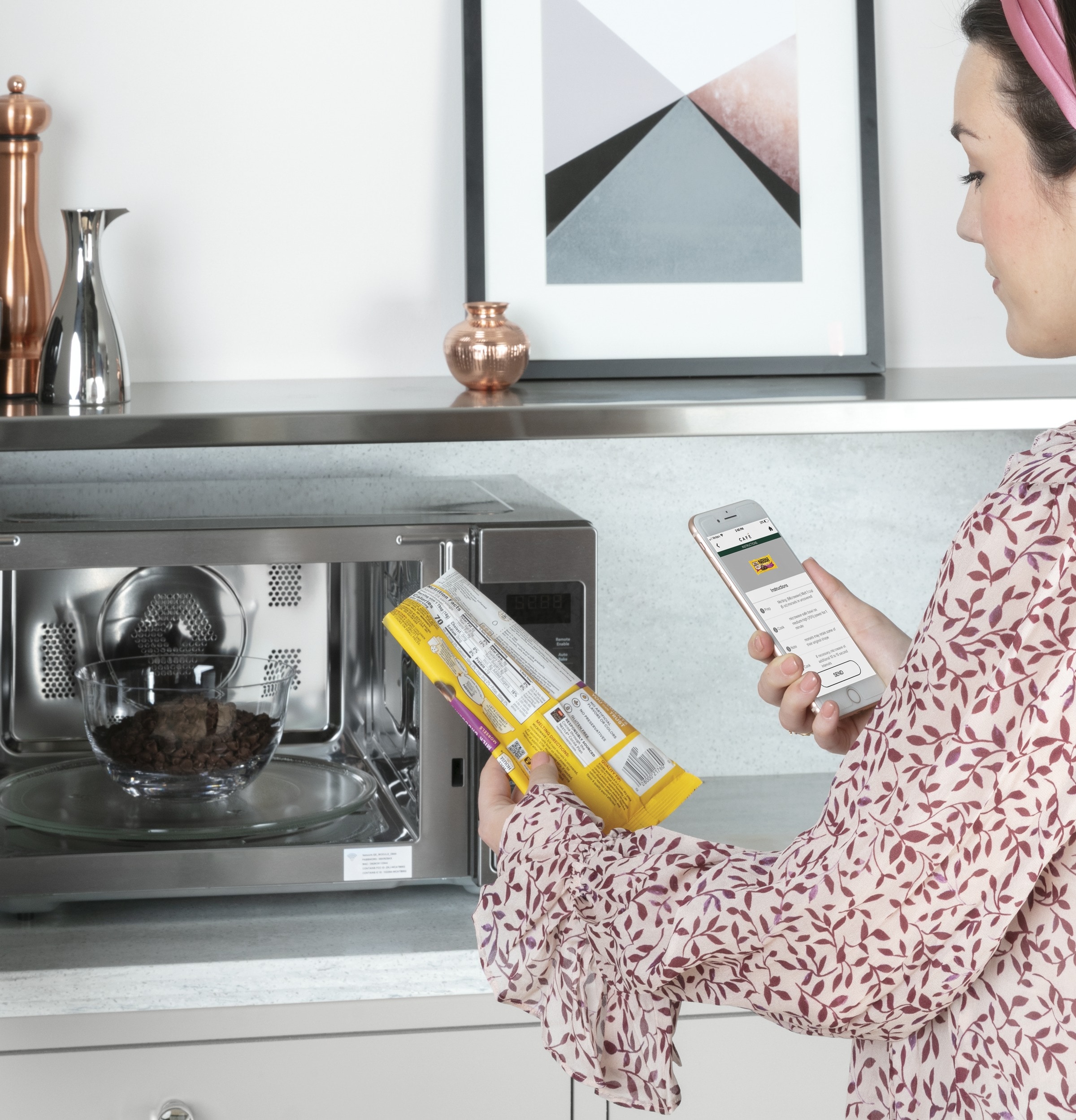 Cafe model CCWK15C1WSS, woman standing next to microwave, scanning a popcorn bag with her smart phone