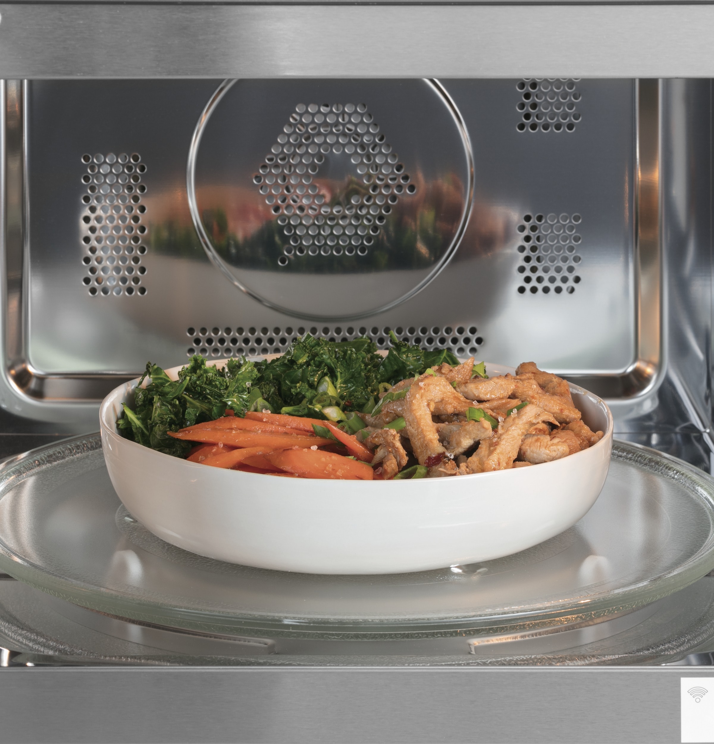 Cafe model CCWK15C1WSS, close up of microwave interior with full bowl of chicken and vegetables