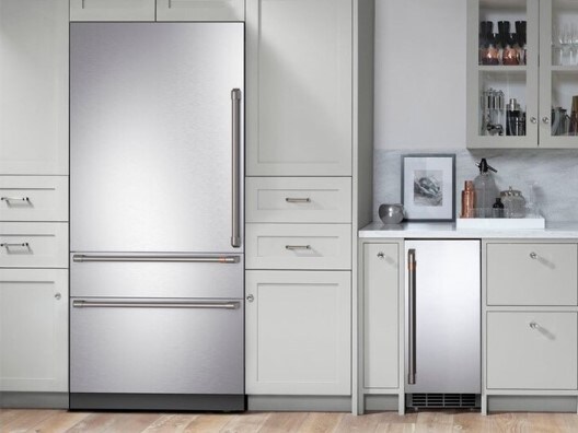 Bottom freezer stainless steel refrigerator in kitchen with white cabinets