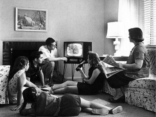 Black and white photo of '50s-era family watching