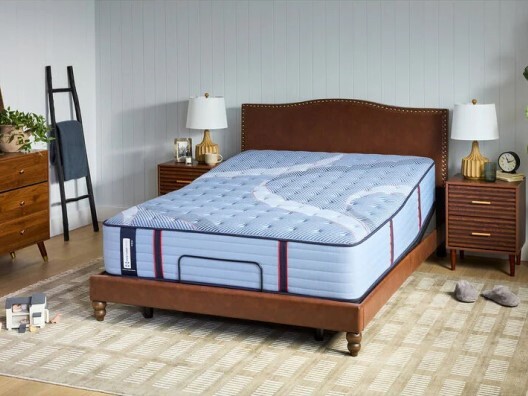 Bare mattress on brown bed frame in bedroom with two matching night stands