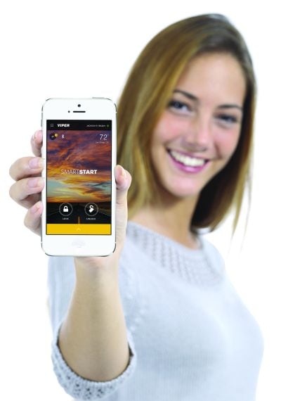 A woman holding a smartphone that is displaying the Viper SmartStart app.