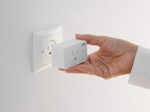 Person's hand plugging a smart plug into a wall outlet
